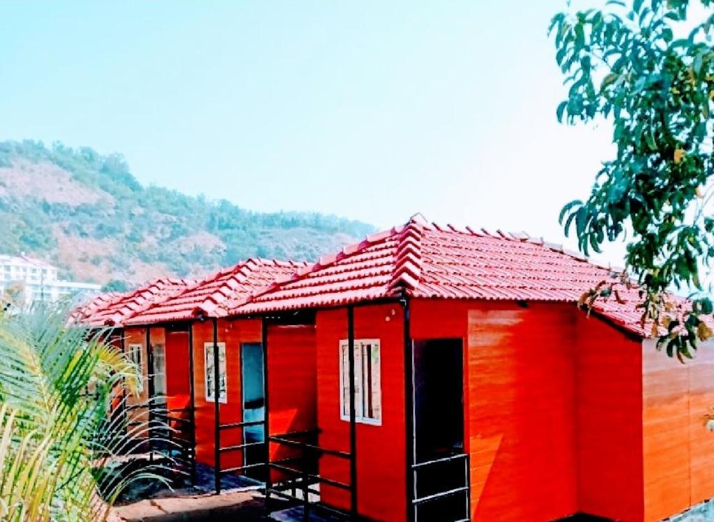 una choza roja con techo rojo en una colina en Western Valley Cottages , Panchagani, en Panchgani