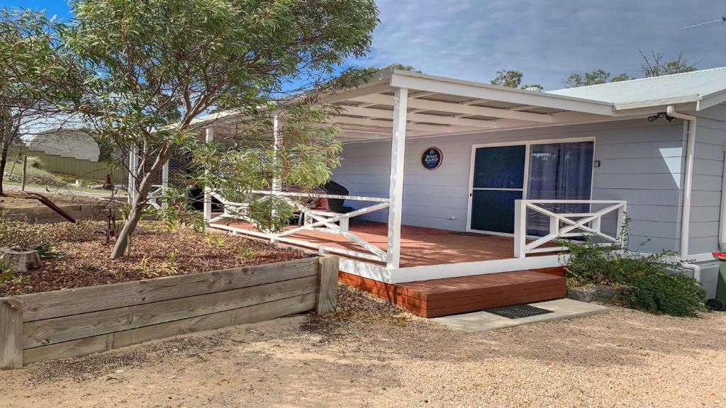 a small white house with a porch and a porch at Boat Ramp Shack in Coffin Bay