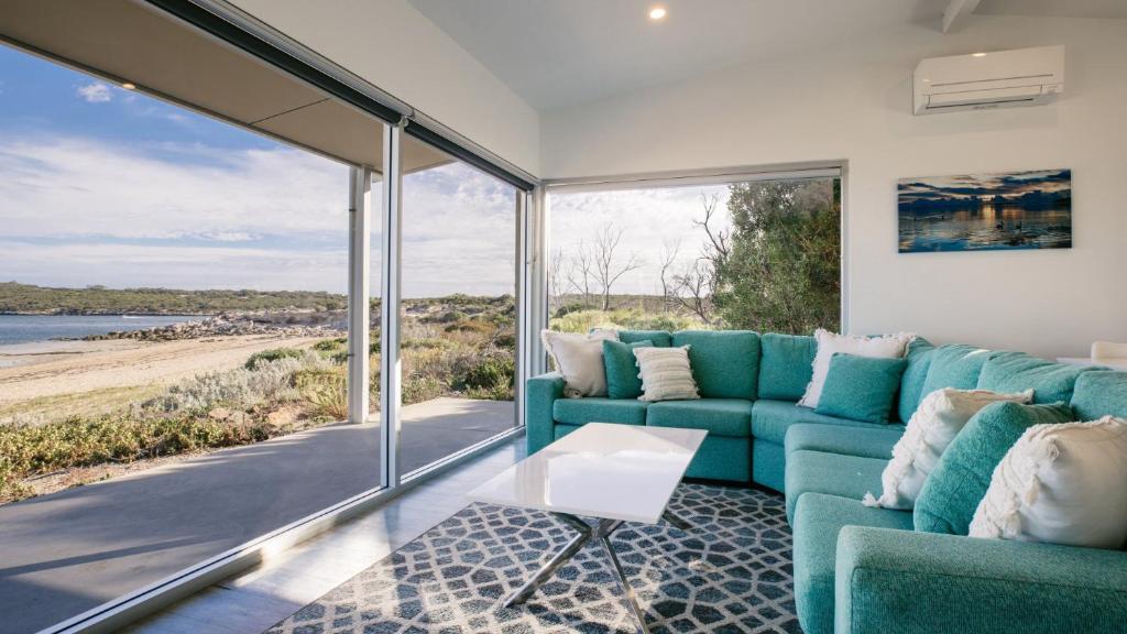 a living room with a blue couch and a view of the beach at Beachside in Coffin Bay
