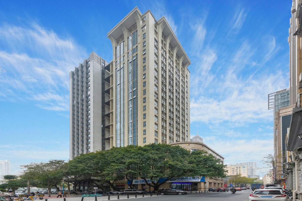 a tall white building with a tree in front of it at WAIFIDEN Duplex Hotel Apartment Zhongyong Jinyu Branch-Free shuttle bus during the Canton Fair in Guangzhou