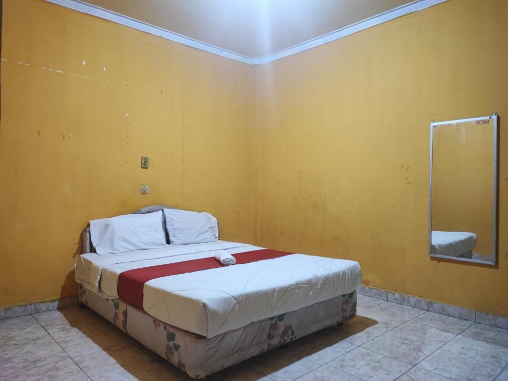 um quarto com uma cama numa parede amarela em RedDoorz Syariah At Hotel Matahari 1 Jambi em Jambi