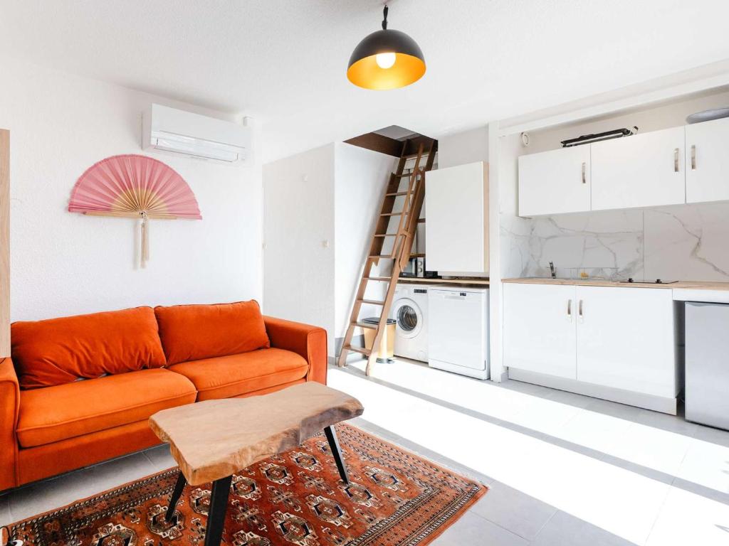 un salon avec un canapé orange et une cuisine dans l'établissement Duplex T2 climatisé, terrasse, proche port - 4 pers. - FR-1-409-254, à Gruissan
