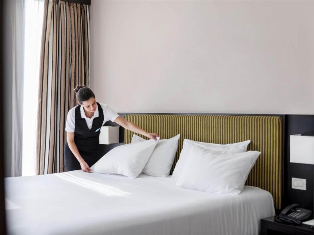 a woman is putting pillows on a bed at Lotus Furnished Hotel Apartments LLC. Ajman in Ajman 
