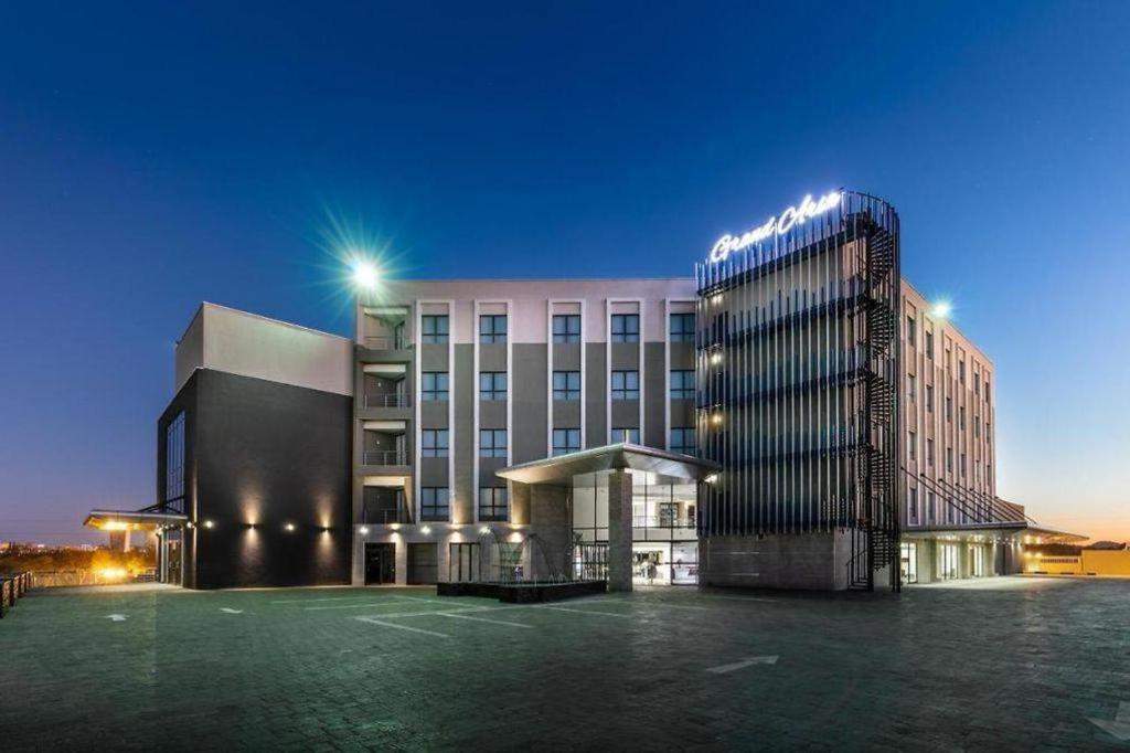un edificio de hotel con un aparcamiento enfrente en Grand Aria Hotel, en Gaborone
