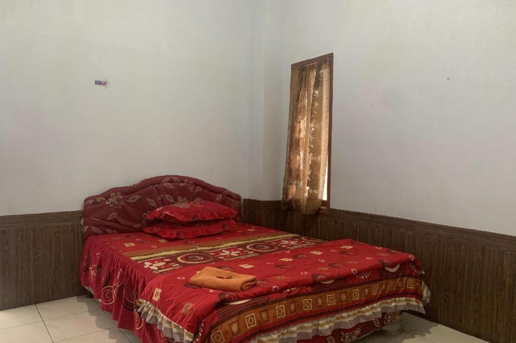 sypialnia z czerwonym łóżkiem i oknem w obiekcie OYO 91263 Dinar Homestay w mieście Manda