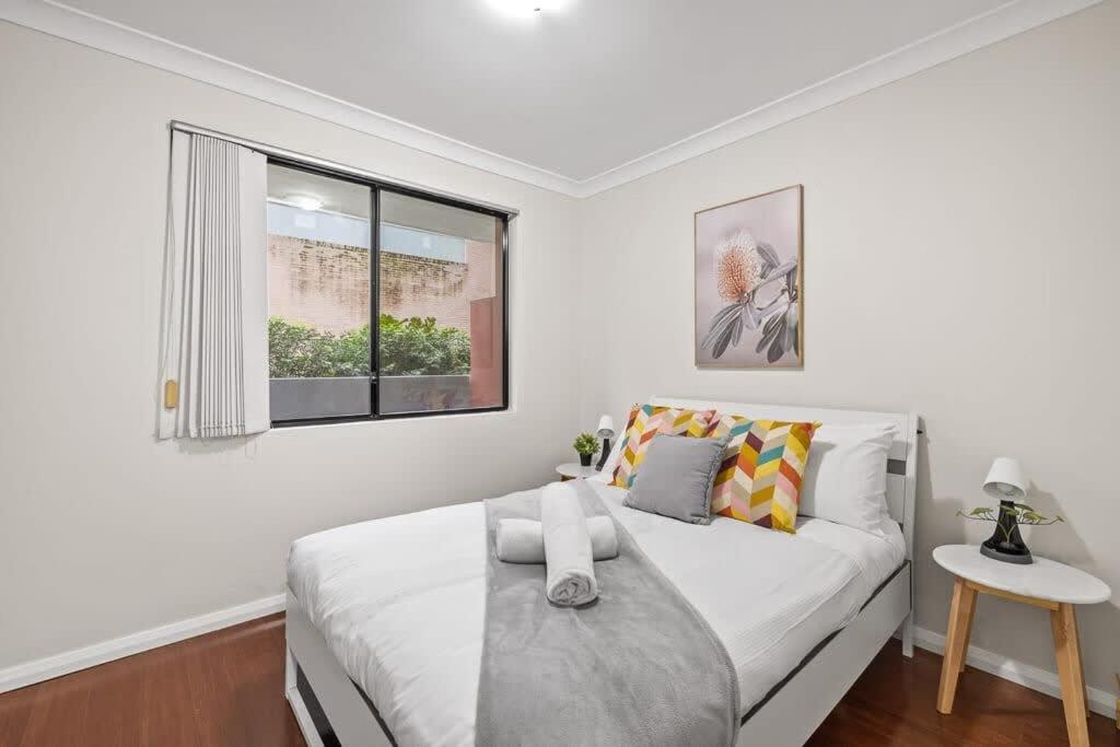 a white bedroom with a bed and a window at 2 Bedrooms Apt in Burwood 4Min To Train Sleep 6 in Sydney