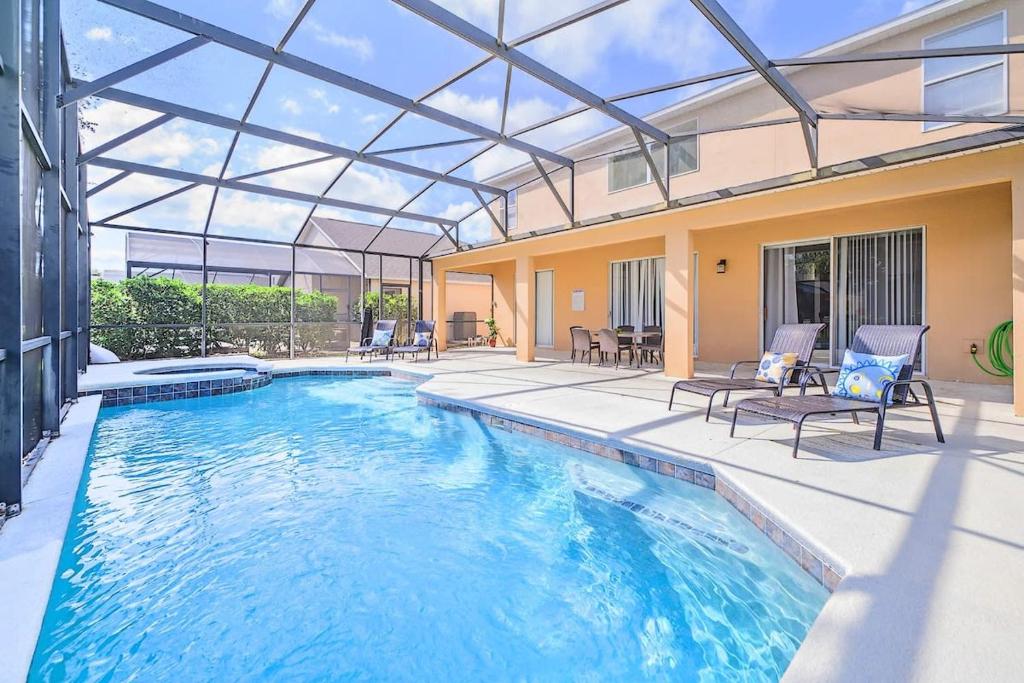 an indoor swimming pool with a glass ceiling and chairs at Near Disney 7BR Home - Pool Hot Tub Games Room in Kissimmee