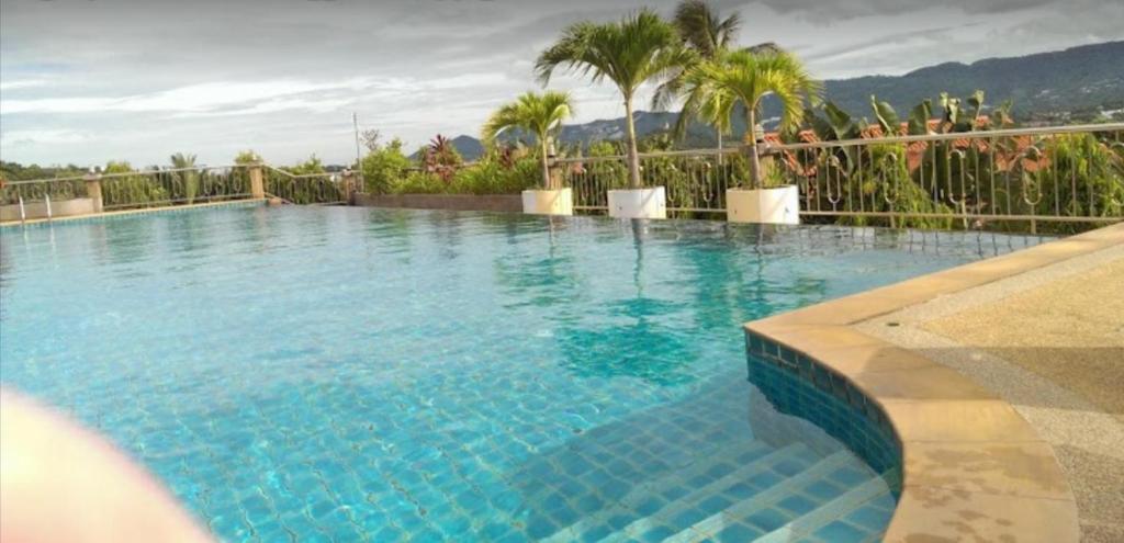 ein großer Pool mit blauem Wasser und Palmen in der Unterkunft Baan Bangrak Garden in Koh Samui 