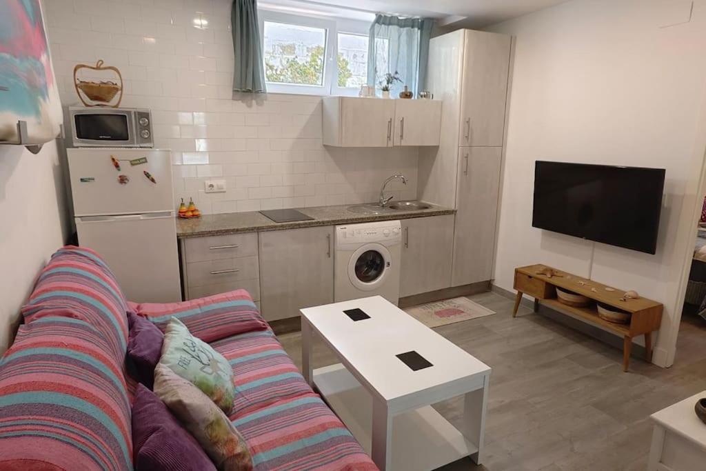 een woonkamer met een bank en een keuken bij Apartamento a pie de playa. in Chiclana de la Frontera