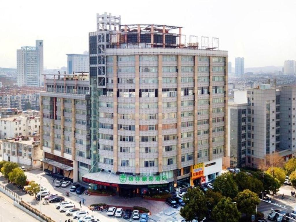 um grande edifício numa cidade com carros estacionados em Green Tree Inn Huainan Square South Road em Huainan