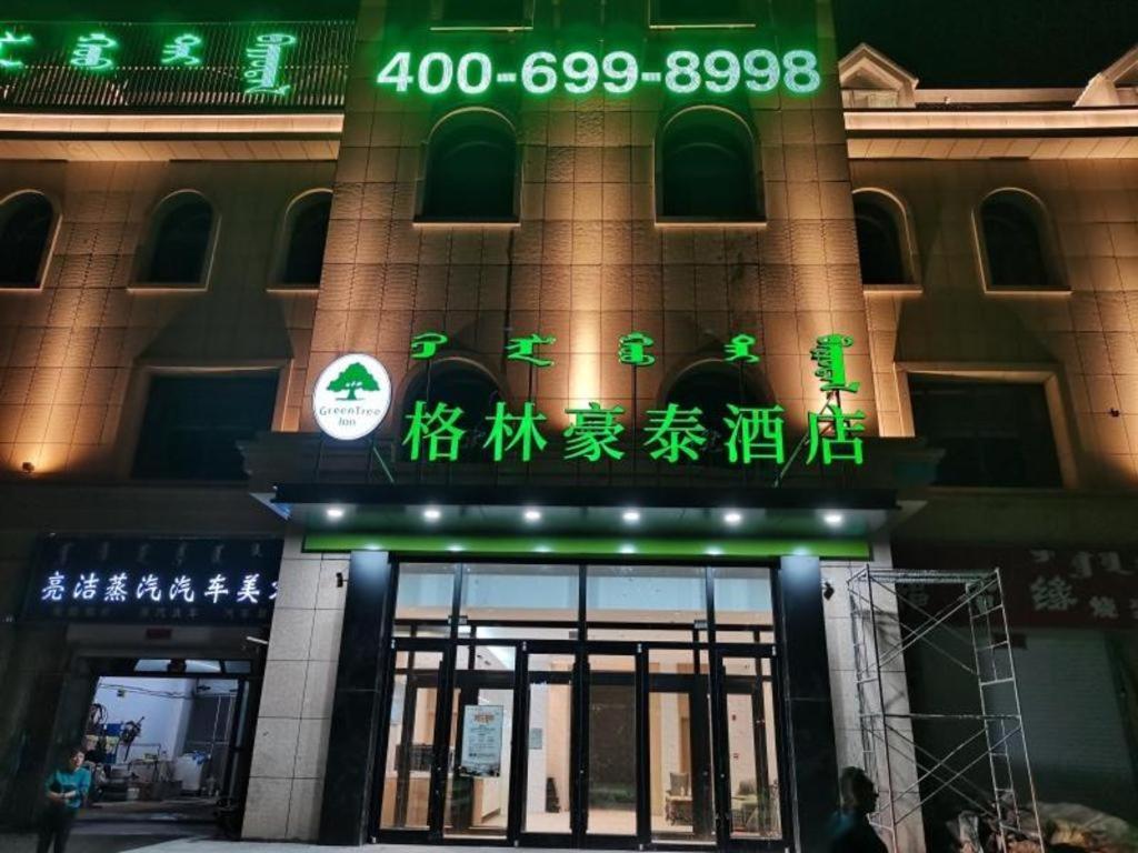 un bâtiment avec des panneaux de néon à l'avant dans l'établissement Green Tree Inn Huhhot Yuquan District South Campus of University of Inner Mongolia, à Hohhot