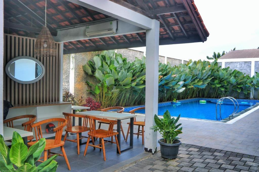 eine Terrasse mit einem Tisch und Stühlen sowie einem Pool in der Unterkunft De Jati House in Cibening Empat