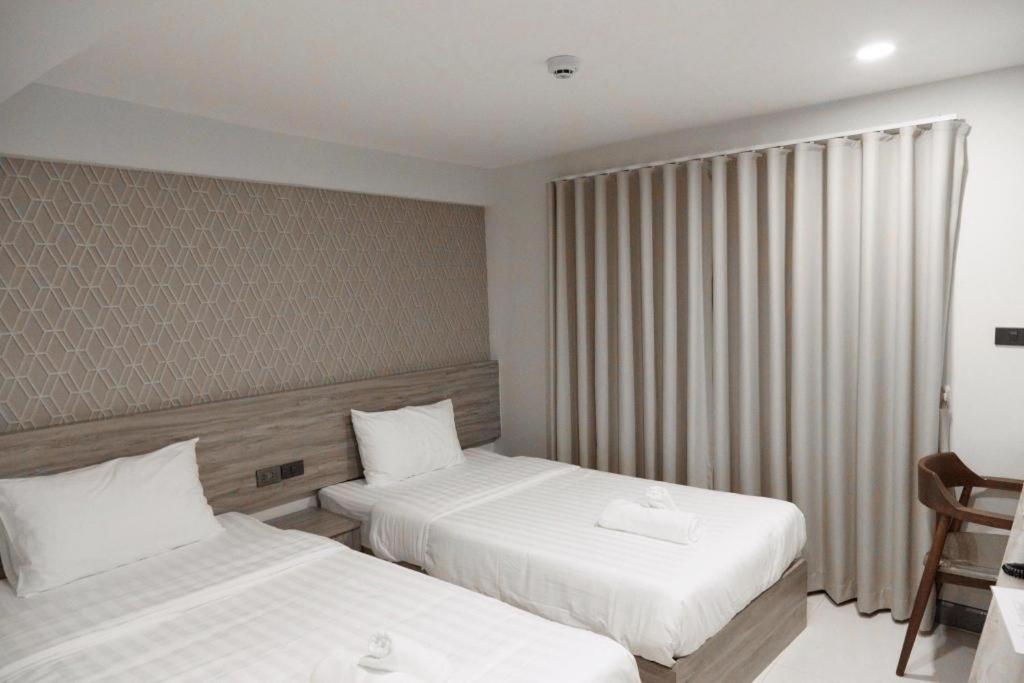 a hotel room with two beds and a chair at SEOUL3 HOTEL & SLOW BAR CAFE in Bangkok