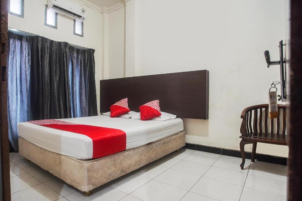 łóżko z czerwonymi poduszkami w pokoju w obiekcie SUPER OYO 3323 Icha Homestay w mieście Sudiang