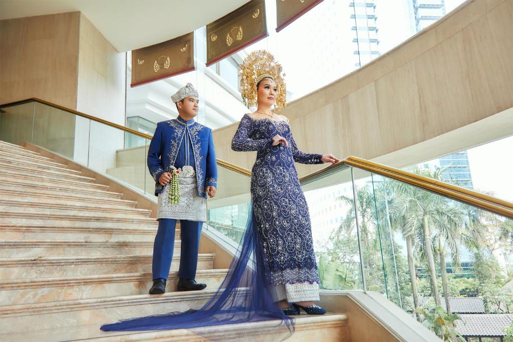 two man and woman standing on stairs in a building at Shangri-La Jakarta in Jakarta