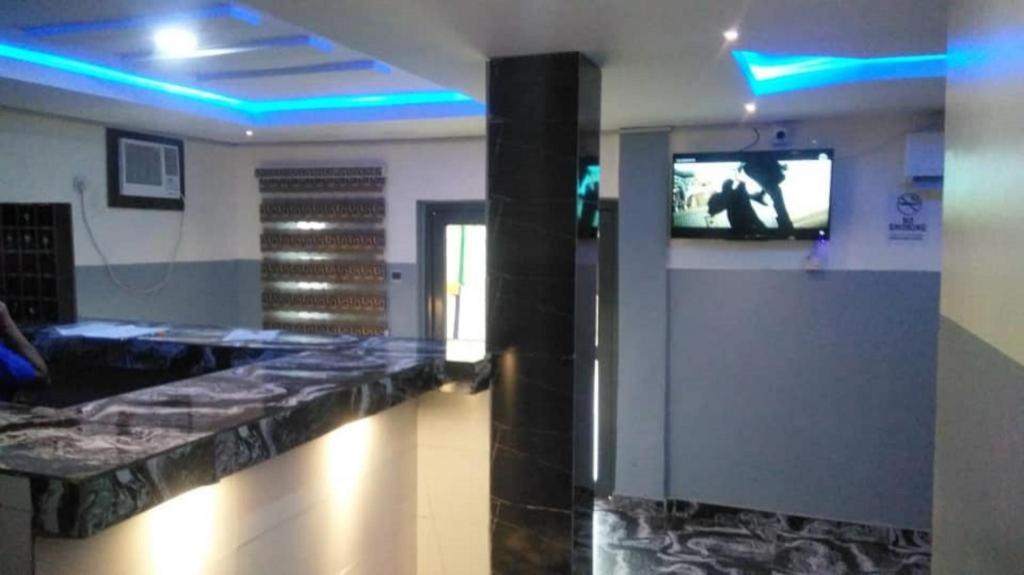um átrio com televisão e um balcão com luzes azuis em Americana Hotel em Oshodi