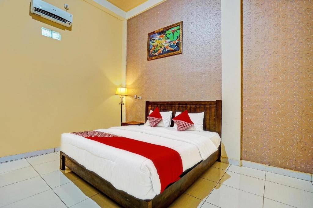 - une chambre avec un grand lit et des oreillers rouges dans l'établissement OYO 92024 Green Hotel, à Jambi