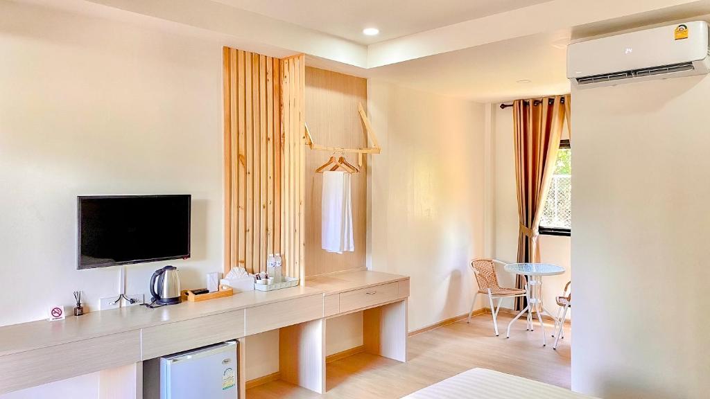 een hotelkamer met een bureau, een tv en een tafel bij น่าน ม่วนใจ Nan Muanjai Hotel in Pua