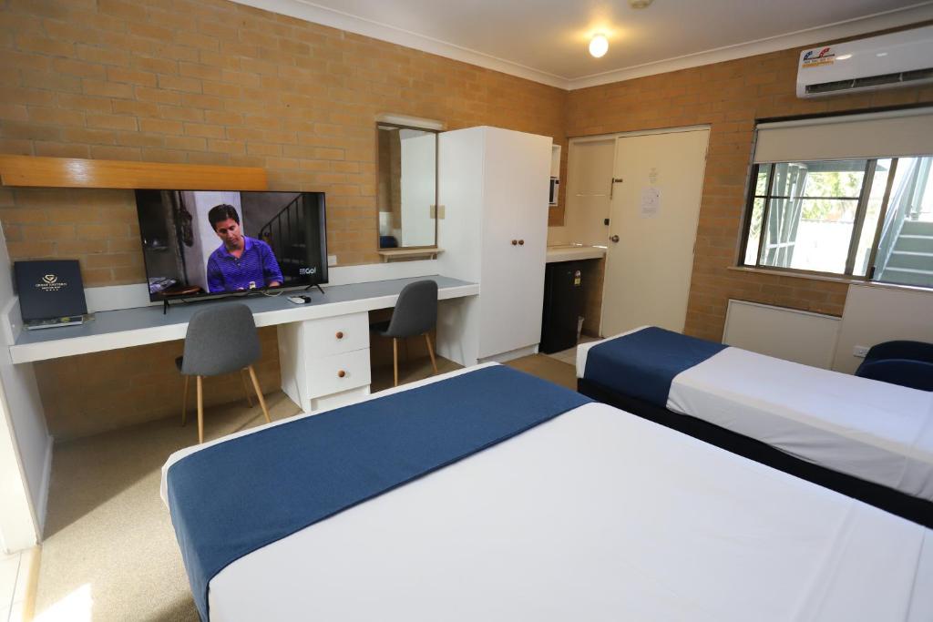 a hotel room with two beds and a television at Great Eastern Motor Inn Gympie in Gympie
