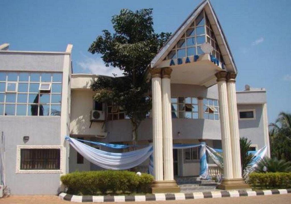 a large white building with a gazebo in front of it at Adap Hotel in Agbabiaka