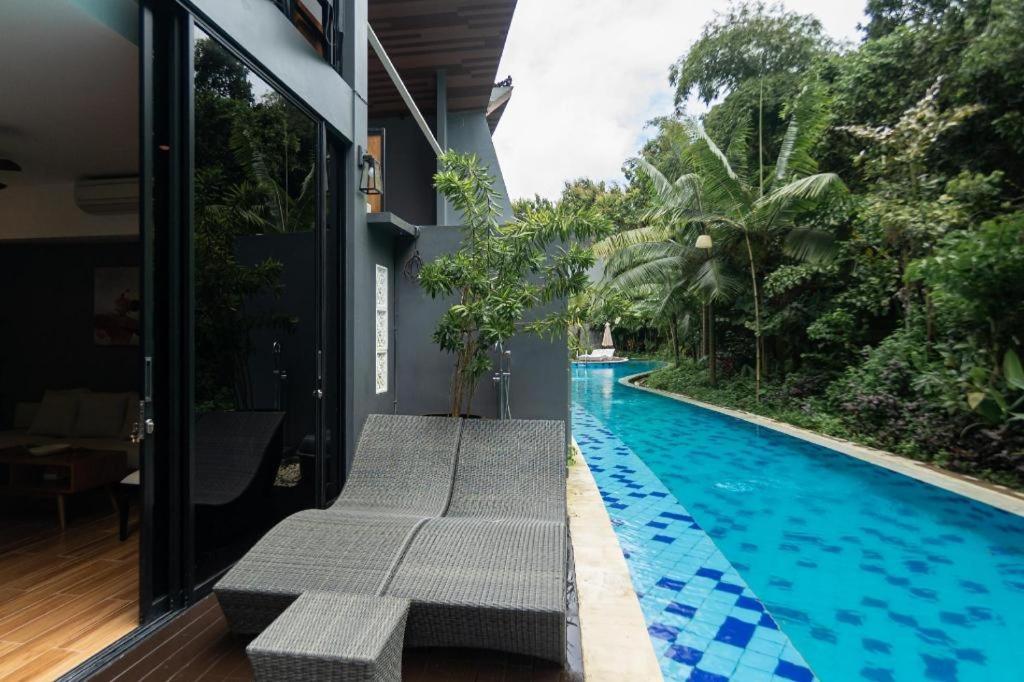 una piscina con panchine accanto a una casa di Coco Ville a Nusa Dua
