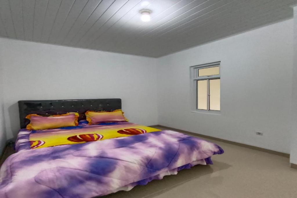 1 dormitorio con 1 cama con edredón morado y ventana en OYO 92504 Guesthouse Porsea en Banualuhu