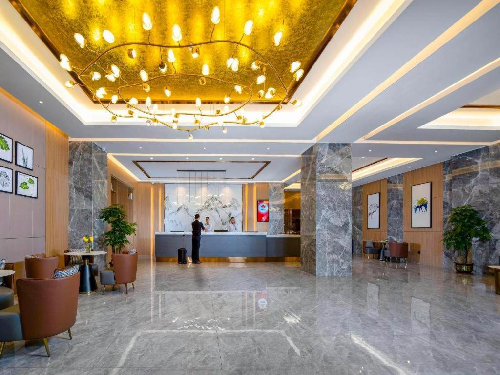 a lobby with a man standing in the middle of a building at Campanile Hotel Shenzhen Guanlan Goft in Tiantangwei