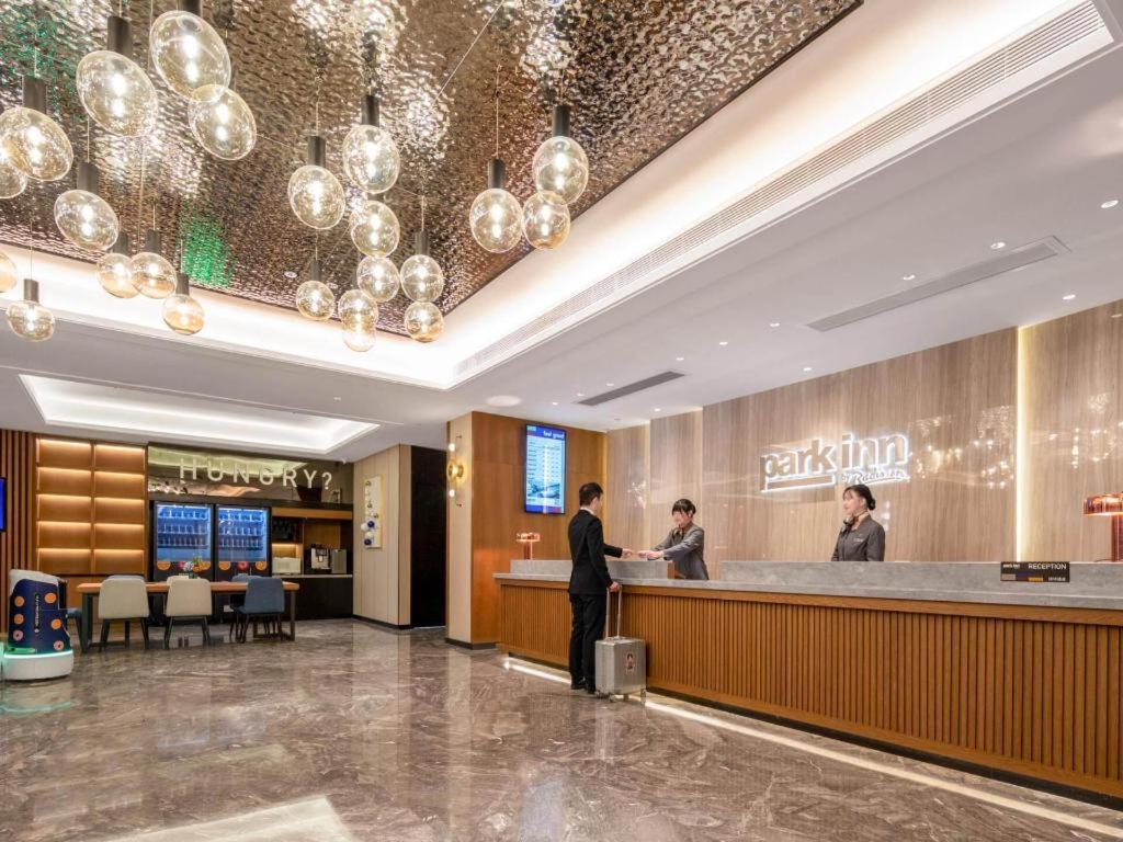 a lobby of a hotel with people standing at a counter at Park Inn Guangzhou Railway Station Yuexiu International Convention Center in Guangzhou