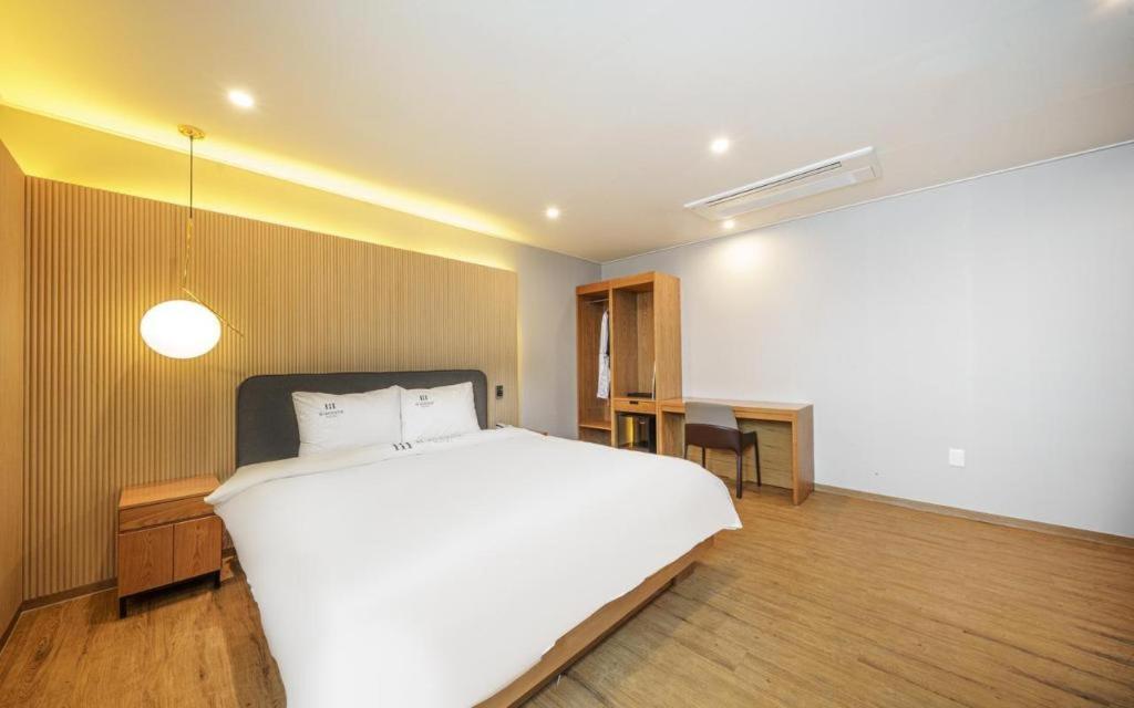 a bedroom with a large white bed and a desk at H Avenue Gyeongju in Gyeongju