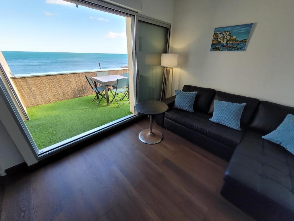 a living room with a couch and a view of the ocean at Front de mer, vue à 180° sur la méditerranée, accès direct plage in Cap d'Agde