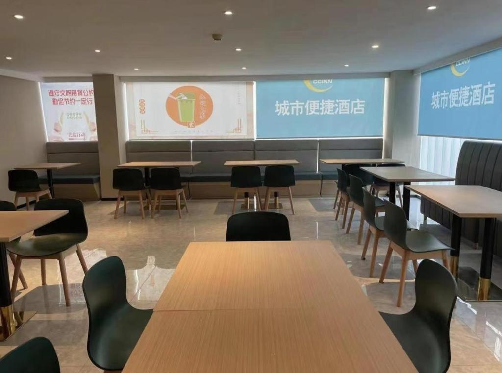 TaheにあるCity Comfort Inn Beijing Capital Airport Shunyi Metro Stationのテーブルと椅子、プロジェクションスクリーン付きの教室