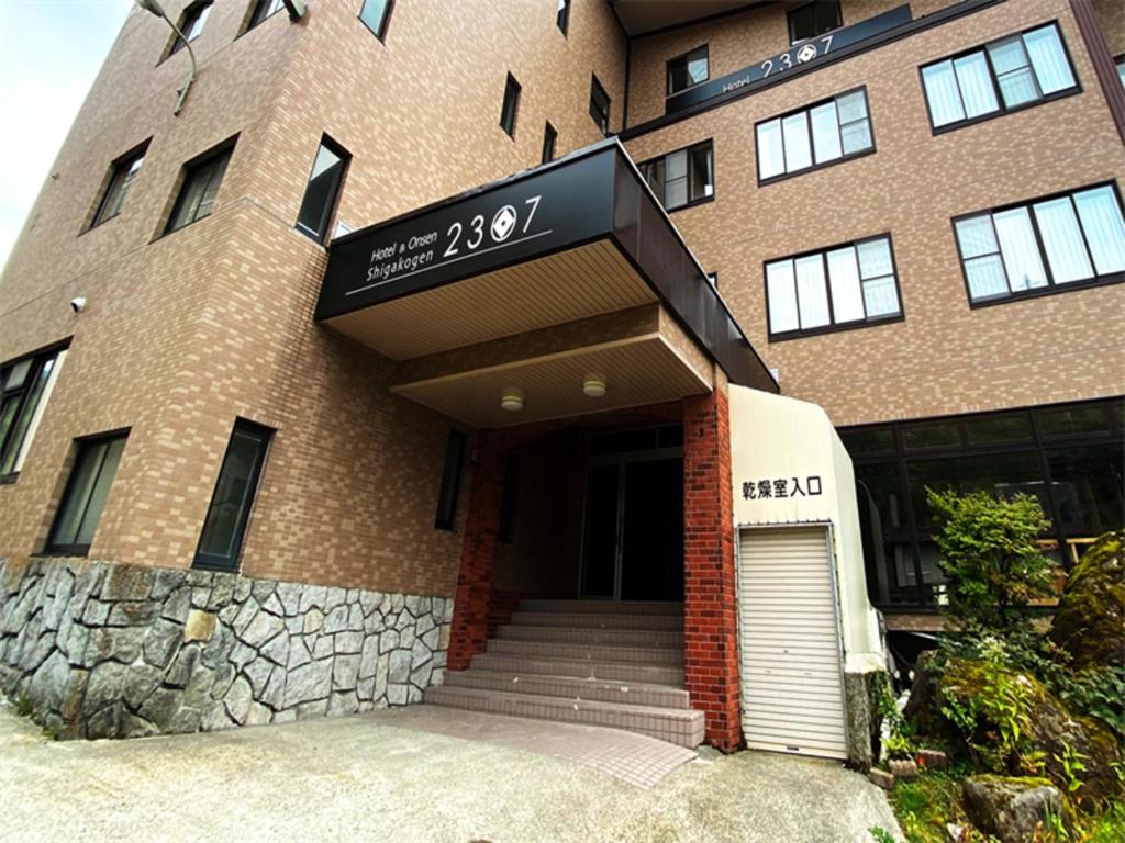 un gran edificio de ladrillo con una puerta delante en Hotel & Onsen 2307 Shiga Kogen, en Shiga Kogen