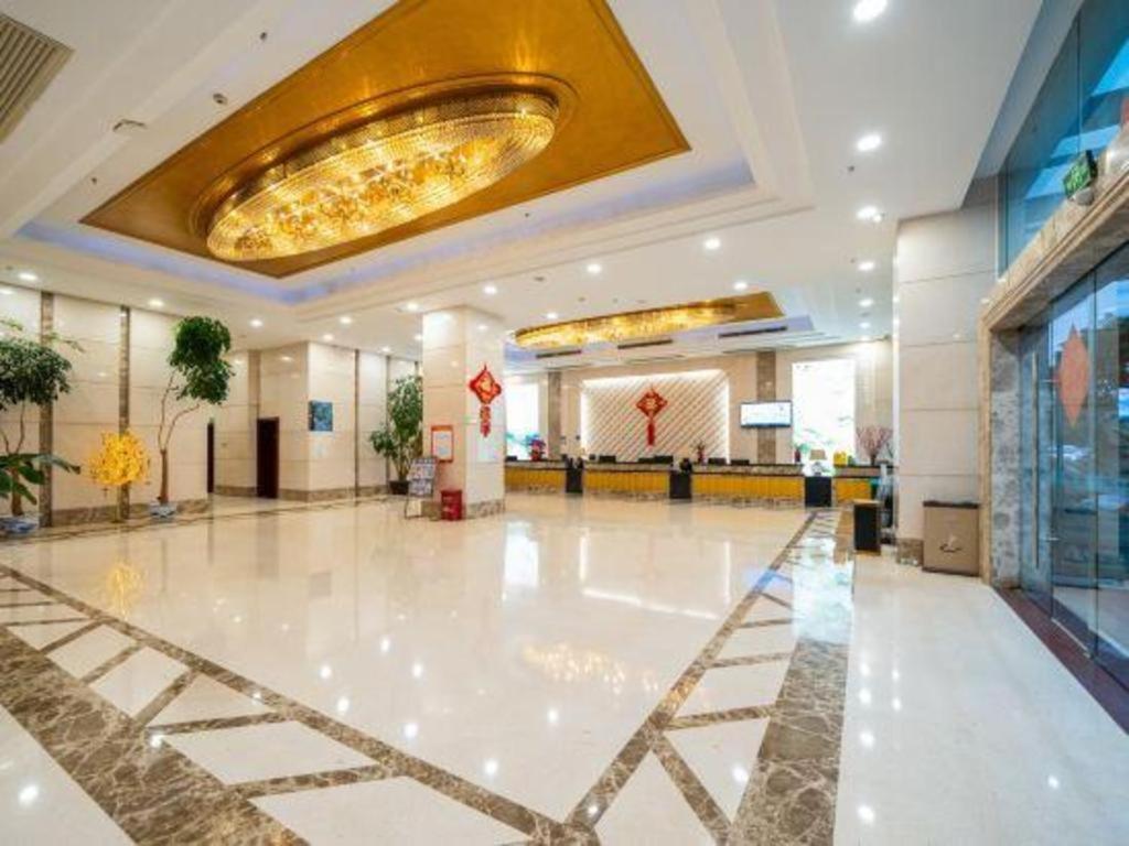 a lobby with a large white floor and a gold ceiling at Bashan Hotel in Heshan