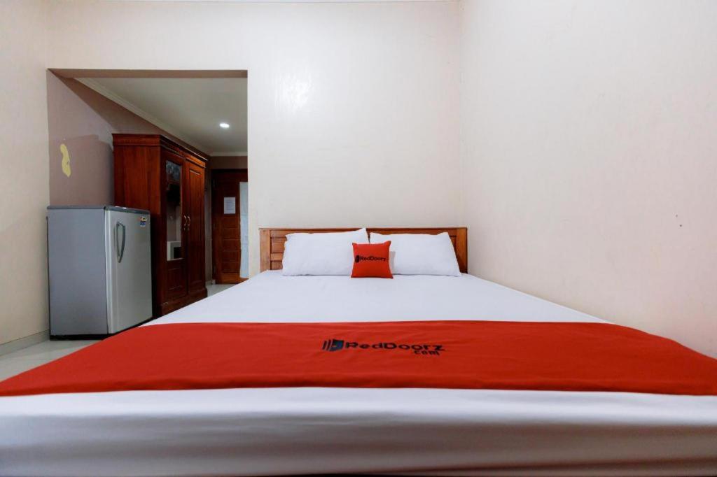 a bedroom with a bed with a red blanket on it at RedDoorz Syariah @ Delta Sari Aloha Waru in Sawotratap