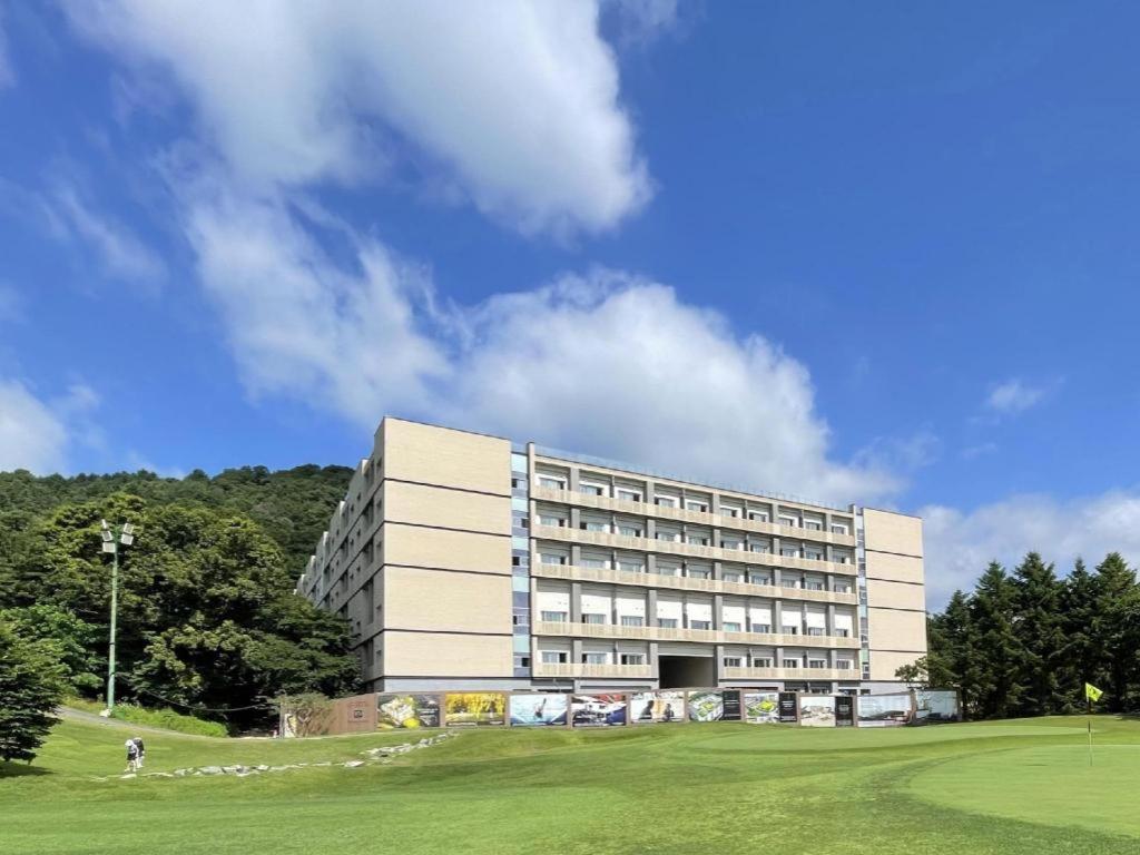 um grande edifício com um campo verde em frente em The Community A by City college em Goyang