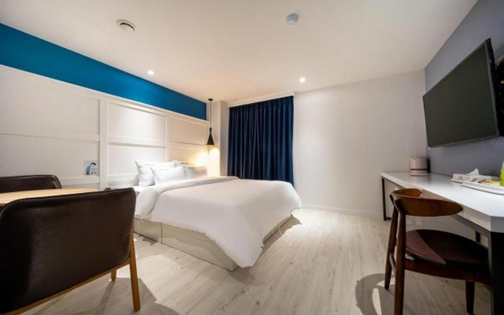 a bedroom with a large white bed and a desk at Wonju Bellino Hotel in Wonju