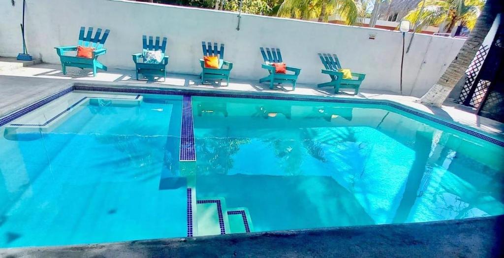 a swimming pool with chairs in front of a building at Casa 3 Salinas Monterrico completamente equipada y con piscina privada in Monterrico