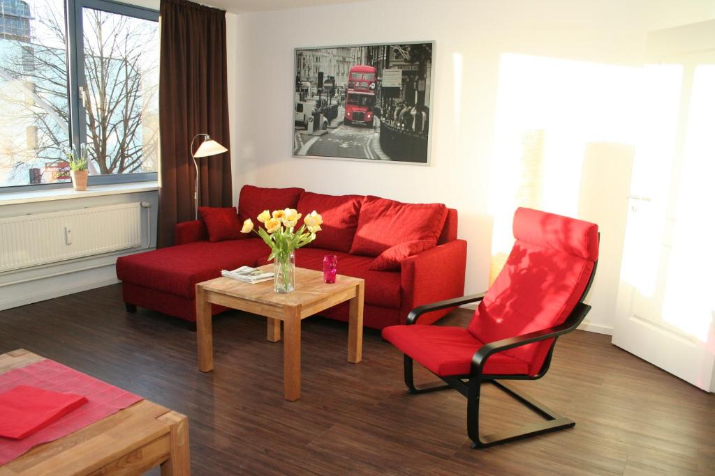 a living room with a red couch and a red chair at APARTHOTEL am Südkanal in Hamburg