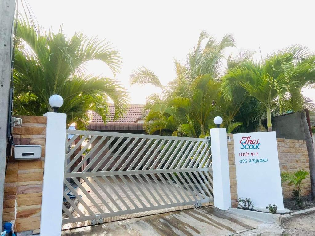 a white gate with a sign on it with palm trees at thai-scout in Pran Buri