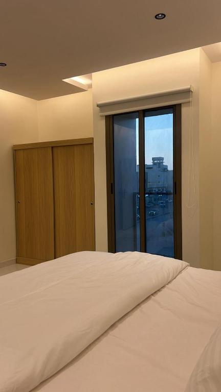 Un dormitorio con una gran cama blanca y una ventana en شقة جديدة بصالة وغرفه نوم ودخول ذاتي مستقل, en Al Kharj
