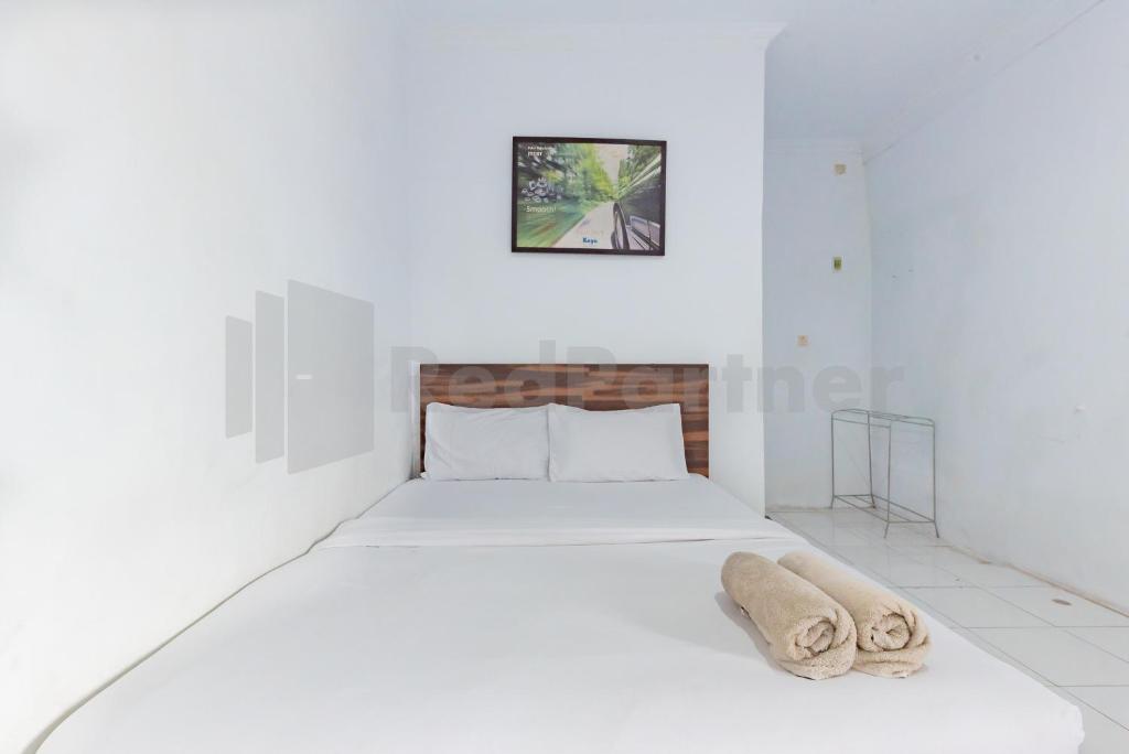 Pondok Tasyiq Syariah RedPartner : غرفة نوم بيضاء مع سرير عليه منشفة