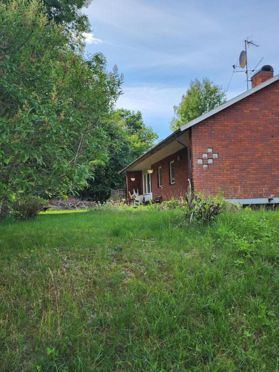 una casa de ladrillo con un patio de hierba delante de ella en Ananis Stuga, en Svartå