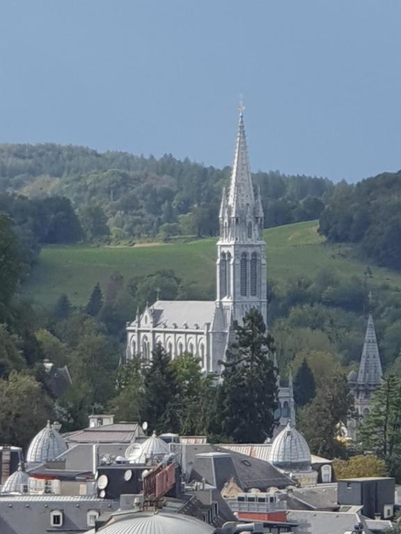 une grande église blanche avec une cloche dans une ville dans l'établissement Maison Cosy, à Lourdes