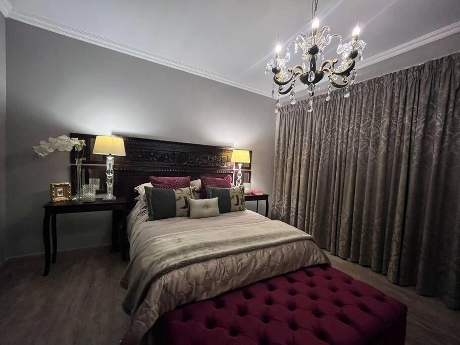 a bedroom with a large bed and a chandelier at Hillside Manor in Dalmada AH
