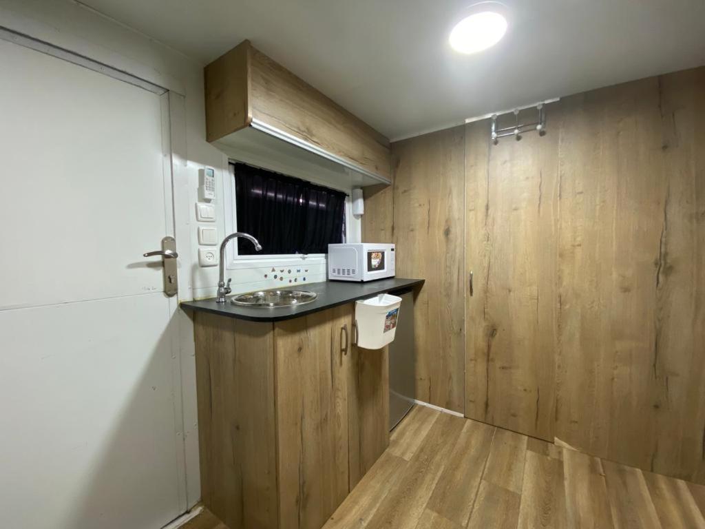 eine Küche mit Holzwänden und einer Theke mit einer Mikrowelle in der Unterkunft קראוון ברעננה in Ra‘ananna
