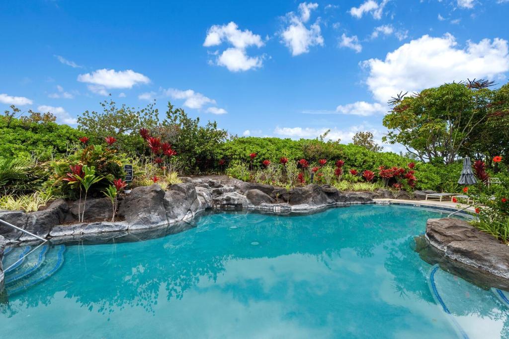 a swimming pool with blue water and flowers at Waikoloa Beach Villas F22 condo in Waikoloa
