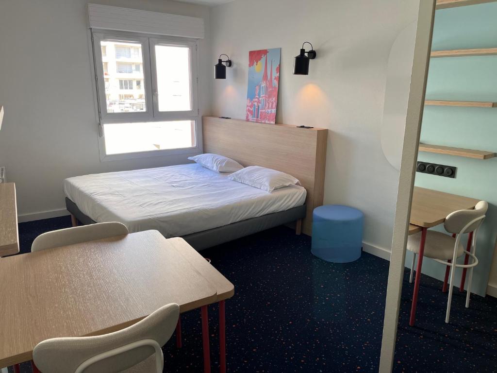 um pequeno quarto com uma cama, uma mesa e cadeiras em Hôtel et Résidence Les Lauréades Clermont-Ferrand Centre Jaude em Clermont-Ferrand