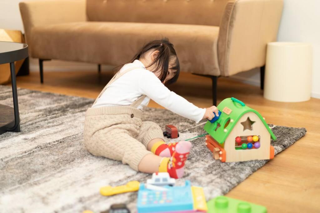a little girl sitting on the floor playing with toys at Fully furnished house for families with infants. in Osaka