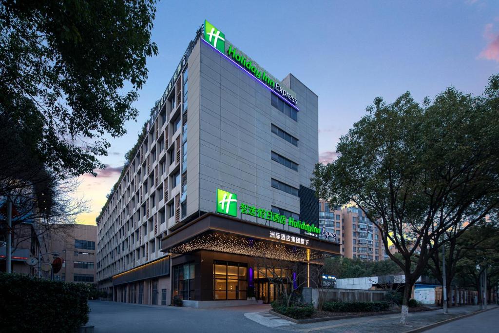 Un palazzo alto con un cartello sopra. di Holiday Inn Express Shanghai Gumei, an IHG Hotel a Shanghai