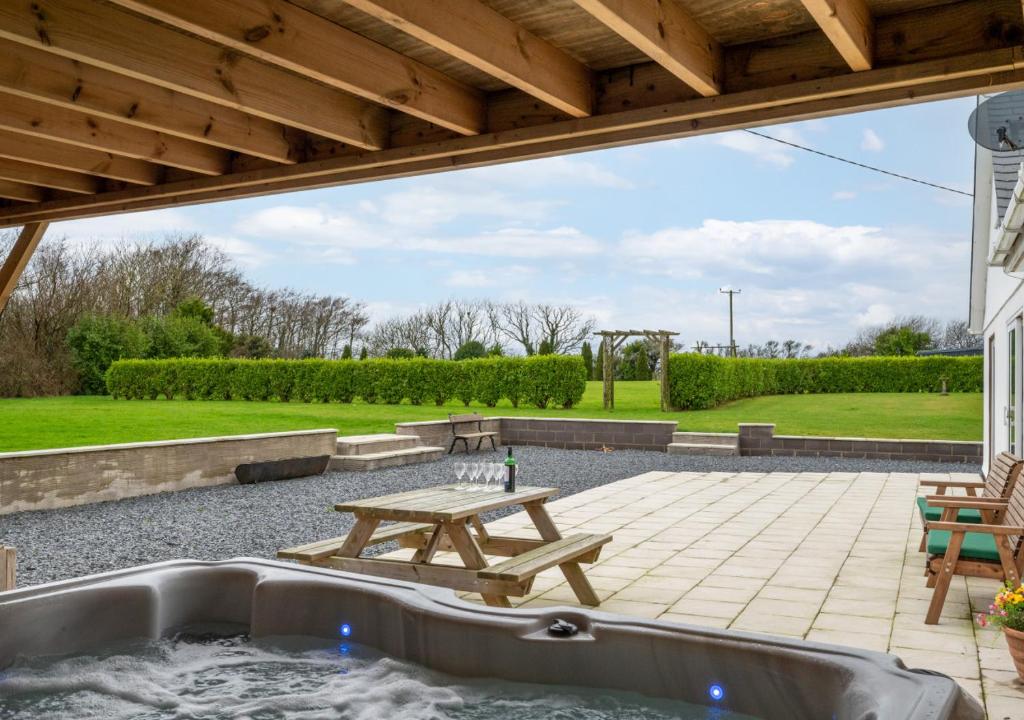 a patio with a hot tub and a picnic table at Llecyn in Pwllheli